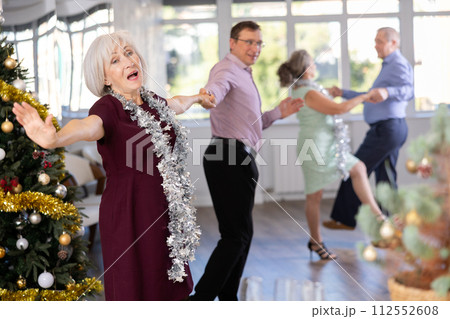 Middle-aged man and elderly woman dancing contemporary discofox in couple in New Year atmosphere Middle-aged man and elderly woman dancing contemporary discofox in couple in New Year atmosphere 112552608