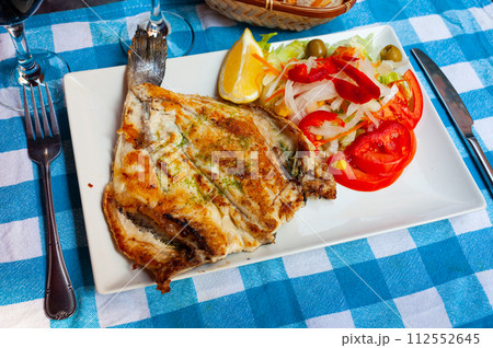 Grilled dorada with pesto, lemon slice and salad of fresh vegetables Grilled dorada with pesto, lemon slice and salad of fresh vegetables 112552645