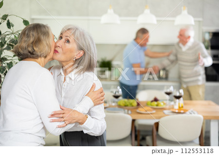 After chatting and gatherings, two mature women friends hug and kiss goodbye. 112553118