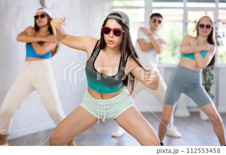 Group of young women and young guy in sunglasses dancing hip hop Group of young women and young guy in sunglasses dancing hip hop 112553458