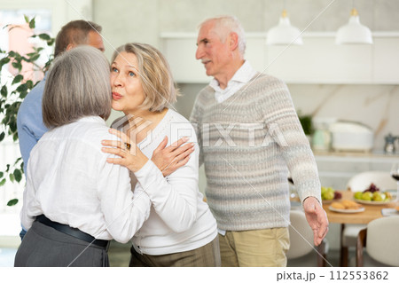 Two elderly women friends hugging in kitchen 112553862