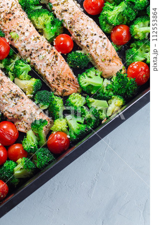 Baked salmon fillet with broccoli and tomato on frying tray, vertical, top view Baked salmon fillet with broccoli and tomato on frying tray, vertical, top view 112553864