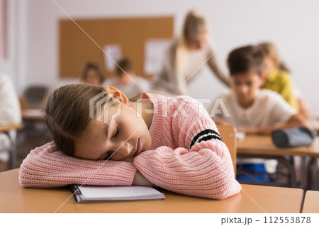 School girl lying and sleeping at desk 112553878