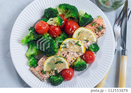Baked salmon fillet with broccoli and tomato on plate, horizontal, top view 112553879