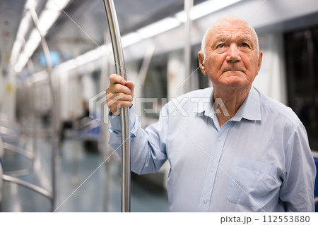 Old man standing in subway car 112553880