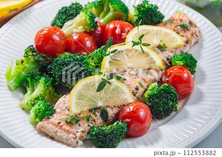 Salmon steak with vegetables, baked salmon fillet with broccoli and tomato, horizontal, closeup 112553882