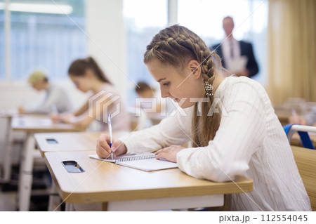 Teen girl sitting at desk in classroom Teen girl sitting at desk in classroom 112554045