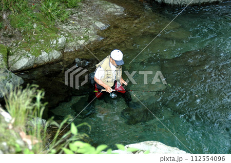 淵の岩壁をへつって上流に釣り遡る釣り人 112554096