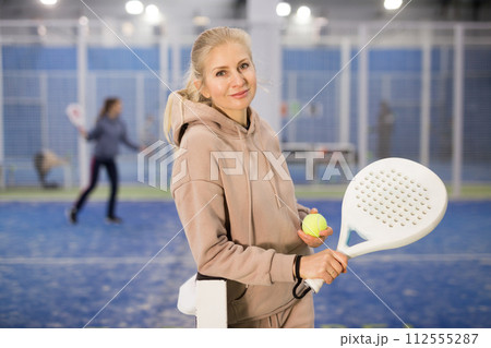 Portrait of young woman with racket and padel ball on tennis court 112555287