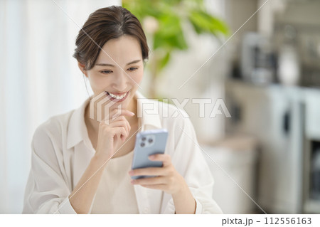 リビングでスマホを見る女性 リビングでスマホを見る女性 112556163