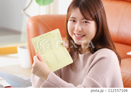 通帳をみて嬉しそうな表情をする女性 通帳をみて嬉しそうな表情をする女性 112557106