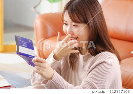 通帳をみて嬉しそうな表情をする女性 112557108
