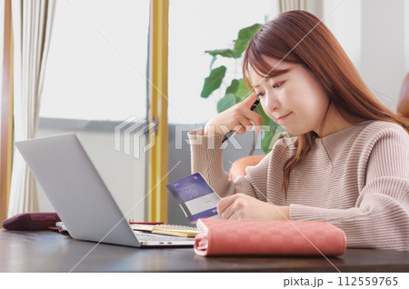 通帳を持って困った表情をしている女性 通帳を持って困った表情をしている女性 112559765