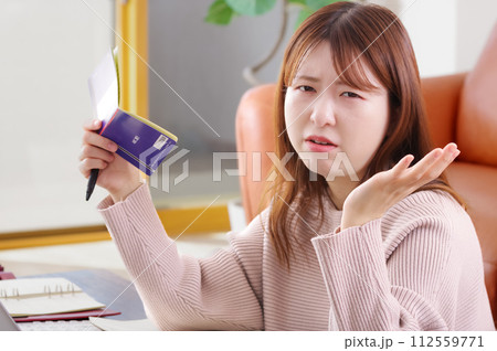 通帳を持って困った表情をしている女性 112559771
