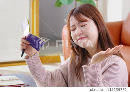 通帳を持って困った表情をしている女性 通帳を持って困った表情をしている女性 112559772