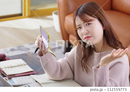 通帳を持って困った表情をしている女性 通帳を持って困った表情をしている女性 112559773