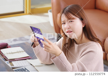通帳を持って困った表情をしている女性 112559774