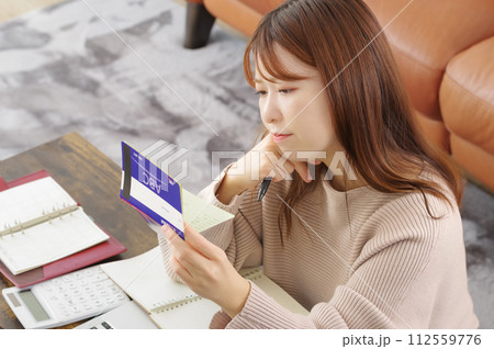 通帳を持って困った表情をしている女性 通帳を持って困った表情をしている女性 112559776