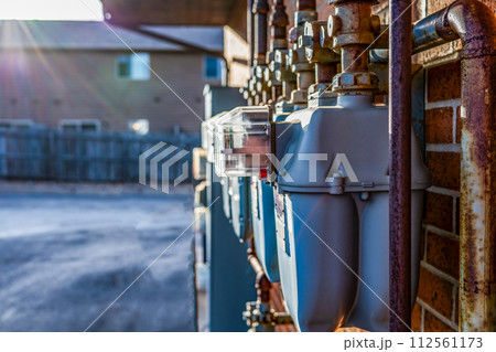 sun flare over a Row of gas utility meters on the outside wall of an apartment building sun flare over a Row of gas utility meters on the outside wall of an apartment building 112561173