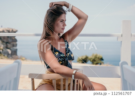 Happy woman portrait in cafe. Boho chic fashion style. Outdoor photo of young happy woman with long hair, sunny weather outdoors sitting in modern cafe. 112561707