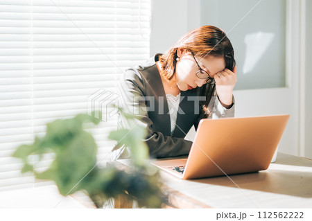 オフィスでノートパソコンを使いながら頭を抱えるスーツ姿の女性 112562222