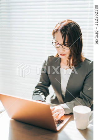 オフィスでノートパソコンを使いながら考え事をするスーツ姿の女性 オフィスでノートパソコンを使いながら考え事をするスーツ姿の女性 112562389