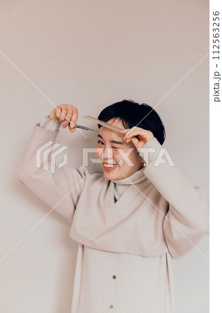 セルフヘアカットをするショートカットのおしゃれな女性 112563256