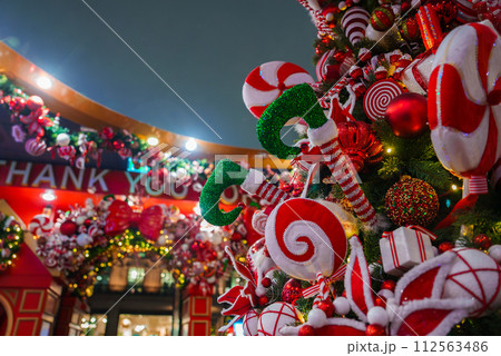 A festive Christmas display in London featuring traditional red, green, and white decorations, including candy canes, baubles, and a garland with a THANK YOU sign, illuminated against a night sky. 112563486