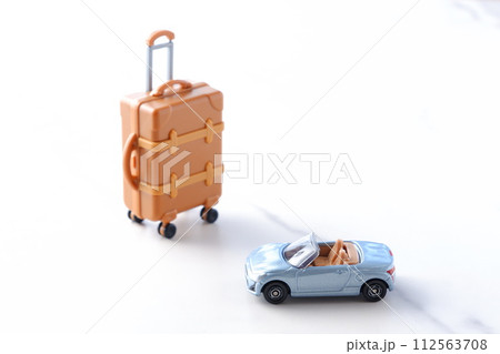 ふたり乗りのオープンカーとスーツケースで、ドライブ旅行へ出発するイメージ 112563708