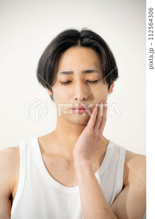 自分の顔を触る若い男性 112564306