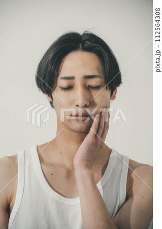自分の顔を触る若い男性 112564308