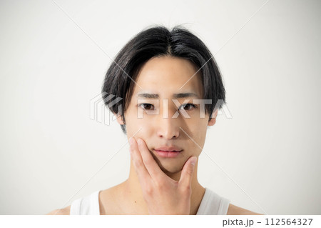 自分の顔を触る若い男性 自分の顔を触る若い男性 112564327
