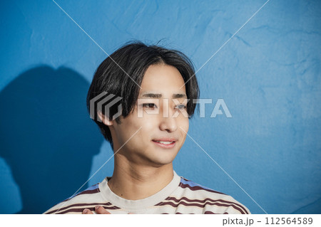 ブルーバックではにかんでいるいる若い男性 112564589