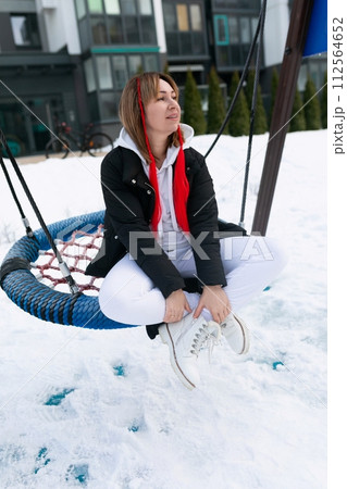 Carefree young woman riding on a swing in winter Carefree young woman riding on a swing in winter 112564652