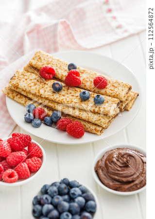 Freshly Made Crepes Topped With Raspberries and Blueberries on white table. Freshly Made Crepes Topped With Raspberries and Blueberries on white table. 112564872