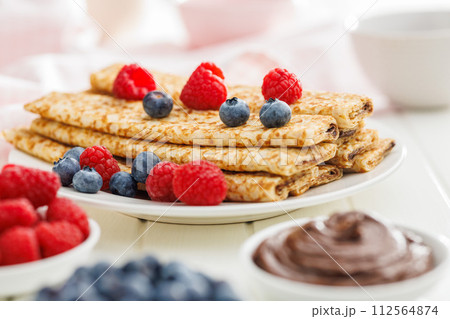 Freshly Made Crepes Topped With Raspberries and Blueberries on white table. 112564874