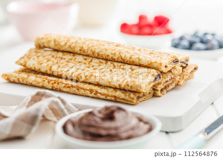 Freshly Made Golden Crepes Stacked on a White Plate, Ready for Breakfast 112564876