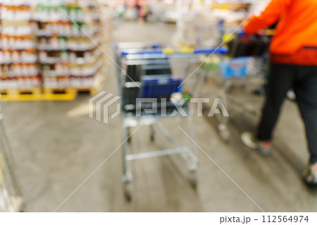 Blurry shot of a shopping cart in a busy store aisle, showcasing the hustle and bustle of shopping activities. 112564974