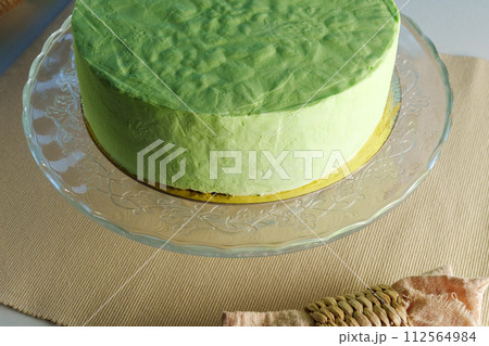 Green cake takes center stage on a glass plate, showcasing its vibrant hue and delicate elegance. 112564984