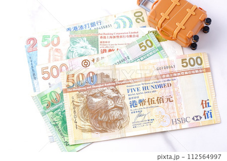 香港の通貨、香港ドル(HKD)の紙幣とスーツケースで、香港旅行のイメージ 香港の通貨、香港ドル(HKD)の紙幣とスーツケースで、香港旅行のイメージ 112564997
