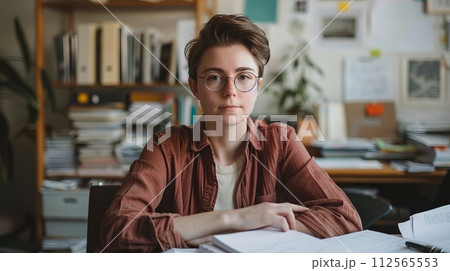 Serious young woman in eyeglasses sitting at desk in office 112565553
