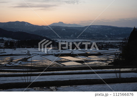 雪解けを待つ棚田の夕景 112566876