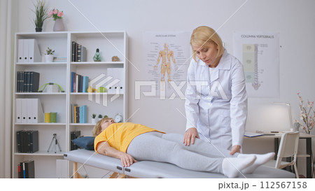 A female orthopedist assesses a patient in a clinic, treating joint pain, and providing healthcare A female orthopedist assesses a patient in a clinic, treating joint pain, and providing healthcare 112567158