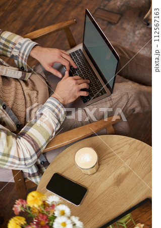Vertical cropped portrait of man typing on laptop keyboard, freelancer working in cafe, using computer in coffee shop 112567163