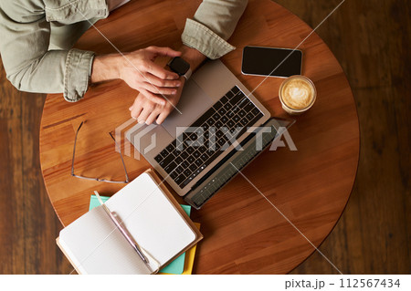 Top view of male hands, man checking time or message on his digital watch, sitting in a cafe with laptop, mobile phone and notebook, drinking coffee Top view of male hands, man checking time or message on his digital watch, sitting in a cafe with laptop, mobile phone and notebook, drinking coffee 112567434