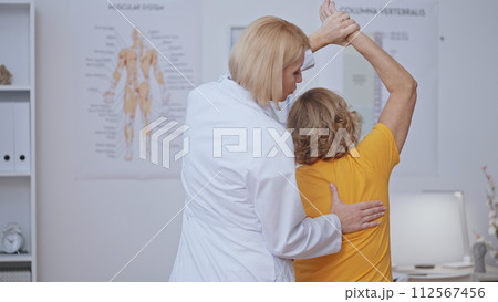 A patient strengthens her muscles with the help of a doctor, receiving physical therapy 112567456