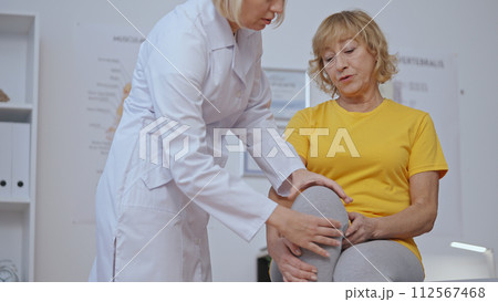 A physiatrist checks a patient's knee at a rehabilitation center, profession of a traumatologist 112567468