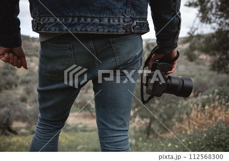 Close-up professional camera in the hands of male traveler photographer Close-up professional camera in the hands of male traveler photographer 112568300