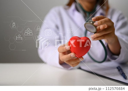Hands of doctor holding stethoscope and red heart. Health insurance and cardiology concept 112570884