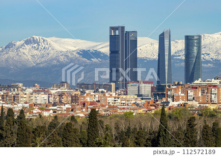 Sierra de Guadarrama. Mountain system seen from the city of Madrid with the recently snow-covered mountains covering the entire top of the mountain range in a white blanket. Skyline next to mountains. Sierra de Guadarrama. Mountain system seen from the city of Madrid with the recently snow-covered mountains covering the entire top of the mountain range in a white blanket. Skyline next to mountains. 112572189